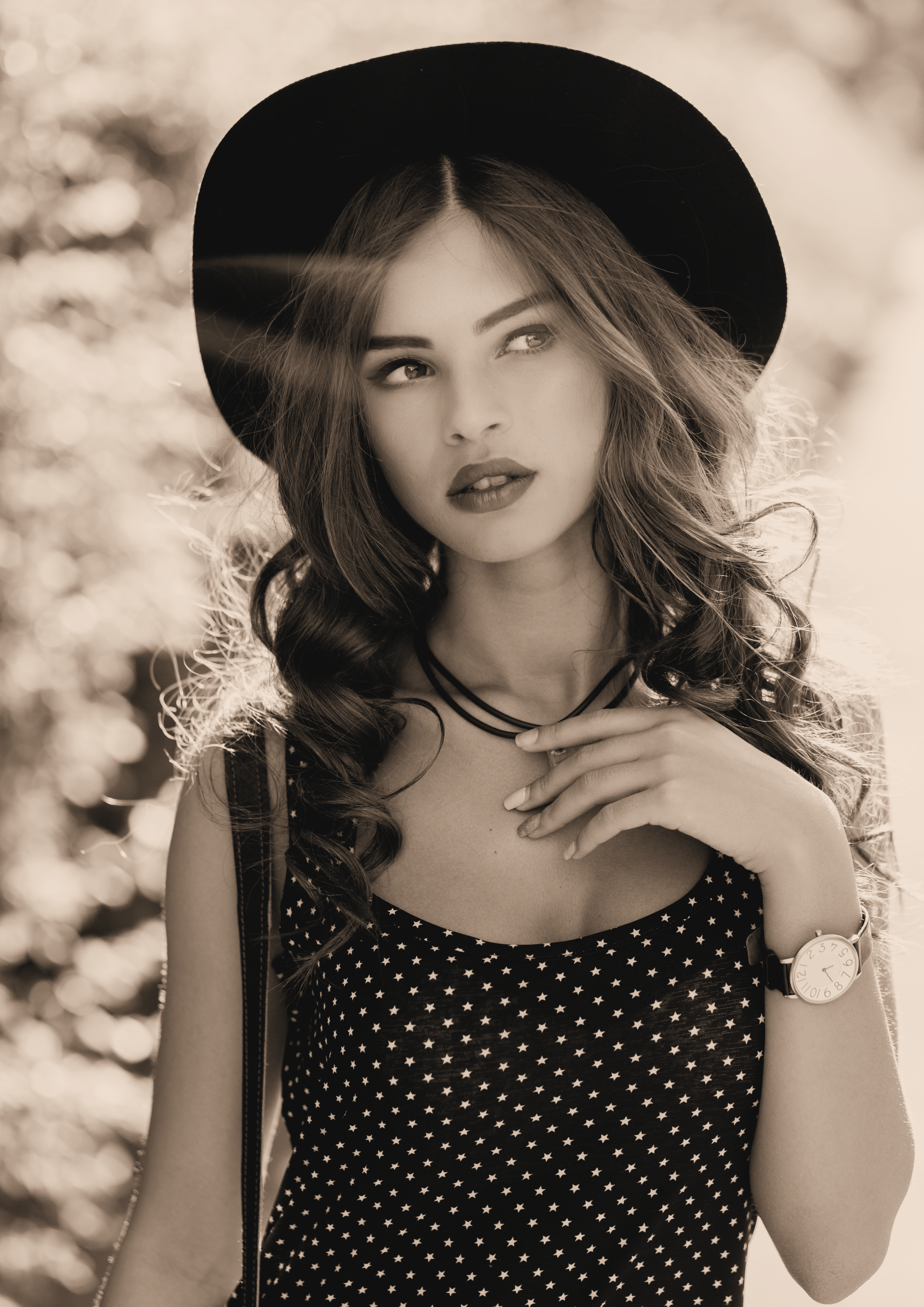 Woman wearing a black hat and polka dot dress with a blurred natural background