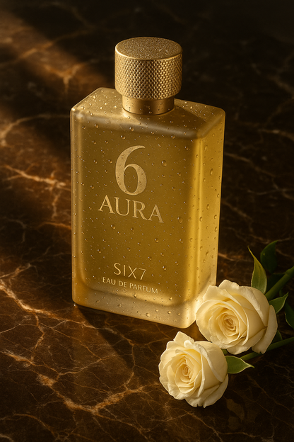 Gold perfume bottle labeled '6 Aura' with white roses on a dark marble surface