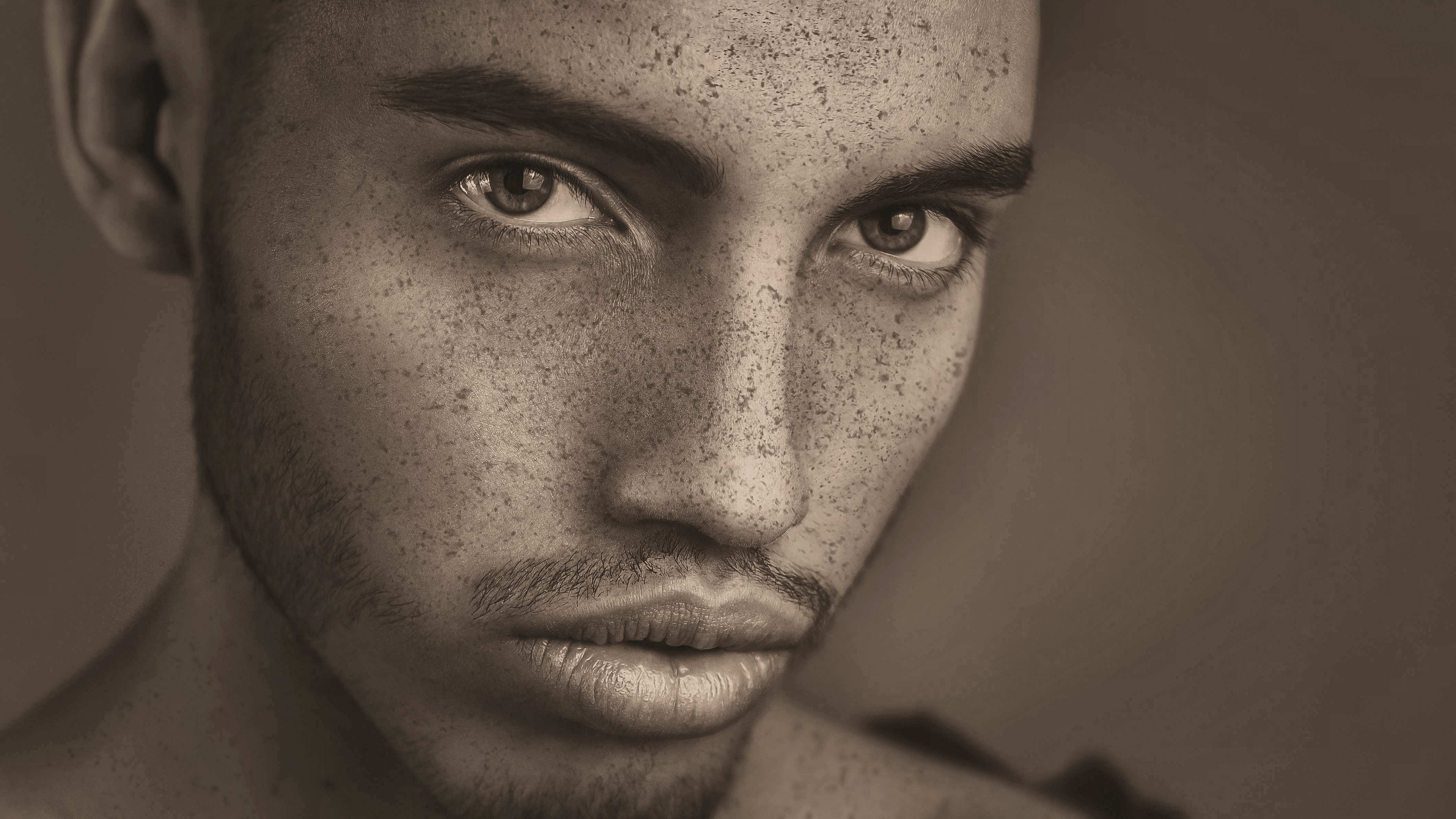 Close-up of a person's face with a neutral expression on a blurred background