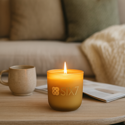 Candle with 'Sia7' branding on a table in a cozy living room setting.